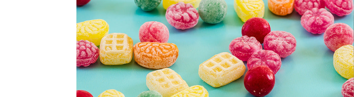 Bunte Bonbons und Süßigkeiten auf türkisem Untergrund – Heißhunger auf Süßes