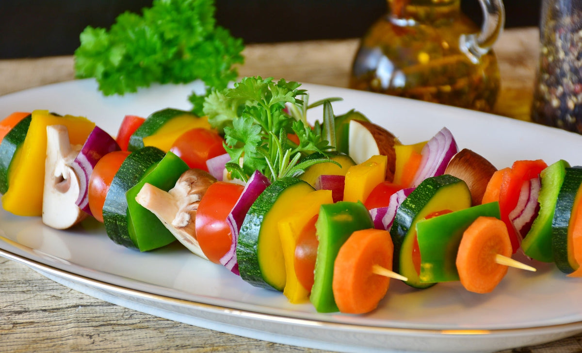 Bunte vegetarische Gemüsespieße mit Zucchini, Paprika, Tomaten, Pilzen und Karotten auf einem Teller
