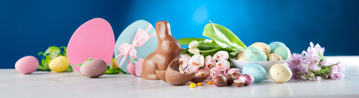 Osterdekoration mit Schokoladenhase, bunten Eiern und Frühlingsblumen